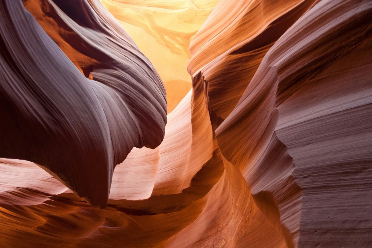 Flowing sandstone walls of a slot canyon glowing orange and violet