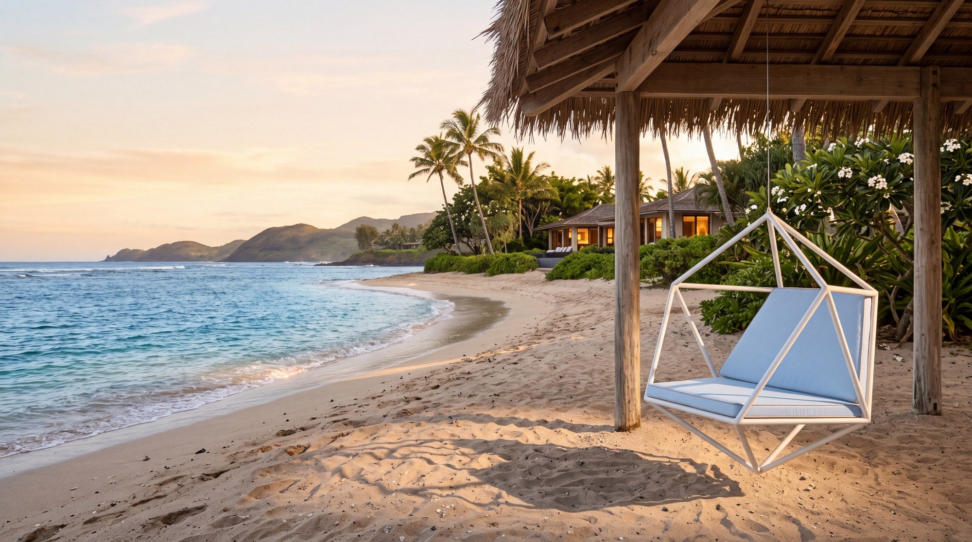 A white Koza 3 swing with powder-blue cushions hanging above the sand of a Hawaiian beach