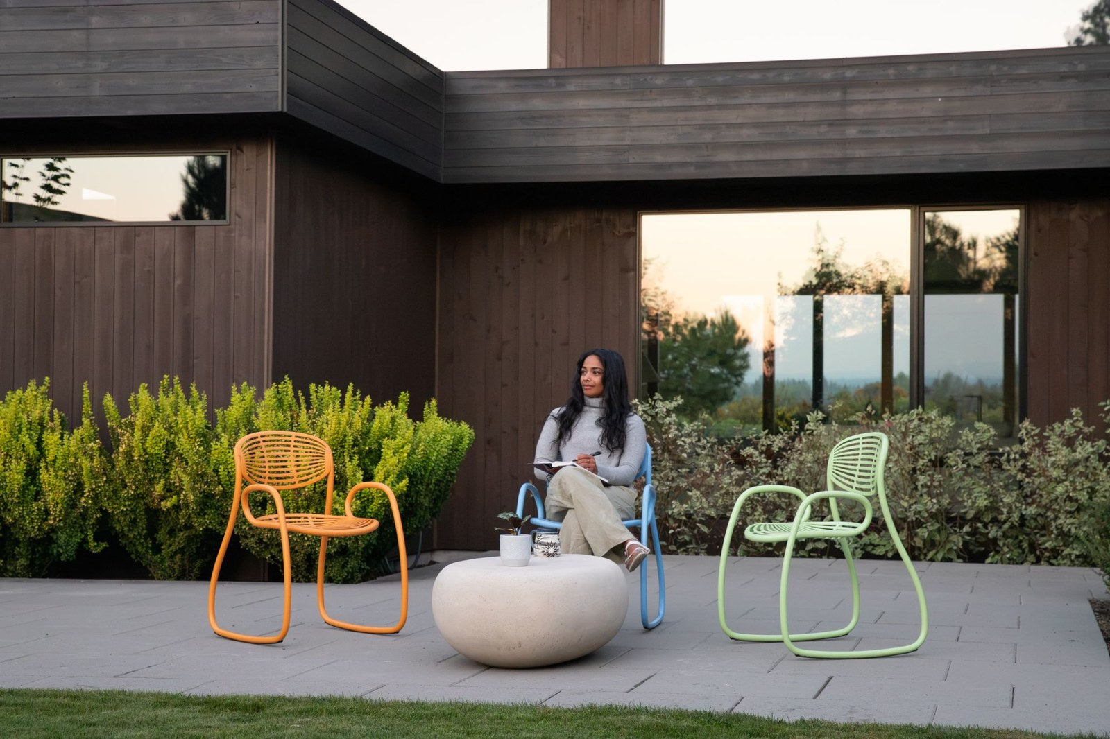 A woman writing in a blue Vibe chair, an orange and a lime green Vibe beside her